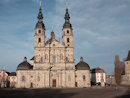 Der Dom ist einer der bedeutendsten barocken Bauwerke Fuldas. Er wurde von dem Architekten Johann Dientzenhofer unter Verwendung der alten Bausubstanz der Ratger- Basilika (9.Jh.) in den neuen Formen des Barocks errichtet (1704-1712). Der Dom ist in seiner architektonischen Gestaltung dem rmischen Barock verpflichtet. Nach umfangreichen Restaurierungsarbeiten erstrahlt der Bau in seinem Inneren und ueren wieder in seinem ursprnglichen barocken Glanz.