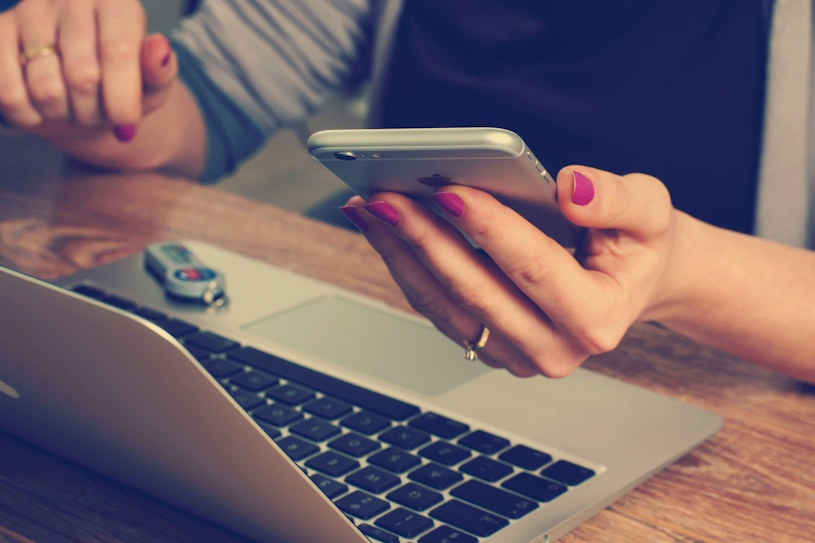 Frau arbeitet mit Smartphone und Laptop