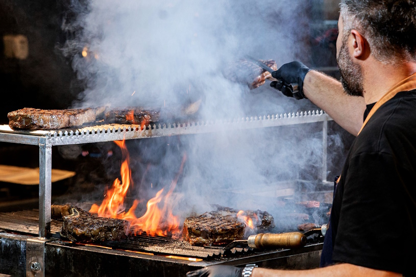 Koch grillt Steaks über offener Flamme Koch grillt Steaks über offener Flamme